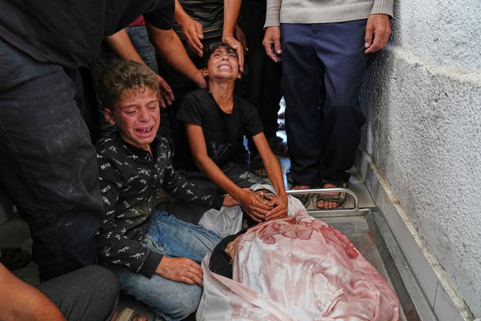 Palestinians children mourn over the body of their father, Mohammed Ghaben, who was killed while heading to an aid distribution hub, at the morgue of the Shifa Hospital in Gaza City, Wednesday, June 18, 2025. (AP Photo/Jehad Alshrafi)