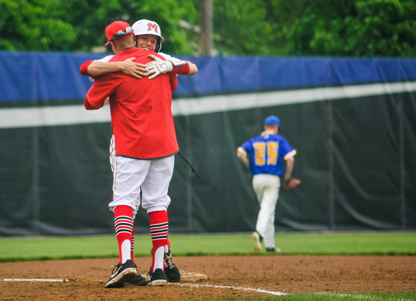 Madison’s Noah Lehman hugs coach Matt Morrison after he connects for a triple during their 4-2 win over Madeira on Wednesday in a Division III district baseball final at Hamilton. NICK GRAHAM/STAFF
