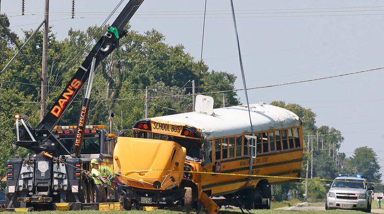 A Northwestern School District bus is uprighted by a crane after it was involved in a crash with another vehicle and rolled over in Lawrenceville, Ohio, Tuesday, Aug. 22, 2023. (Bill Lackey/The Springfield News-Sun via AP)