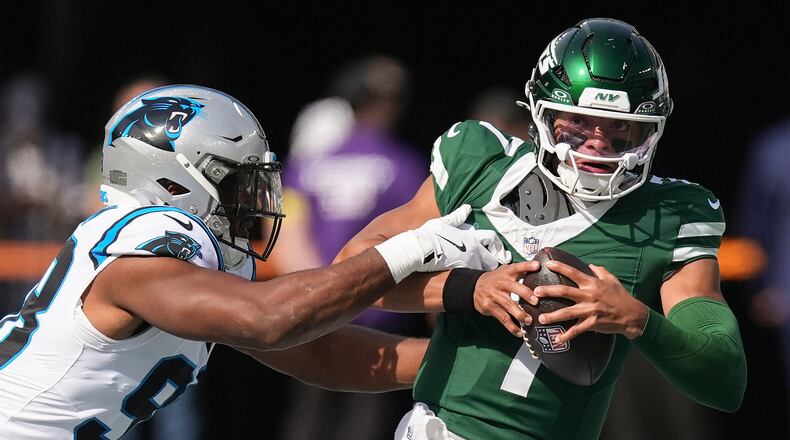 New York Jets quarterback Justin Fields (7) tries to avoid a tackle by Carolina Panthers linebacker D.J. Wonnum (98) during the first quarter of an NFL football game, Sunday, Oct. 19, 2025, in East Rutherford, N.J. (AP Photo/Seth Wenig)