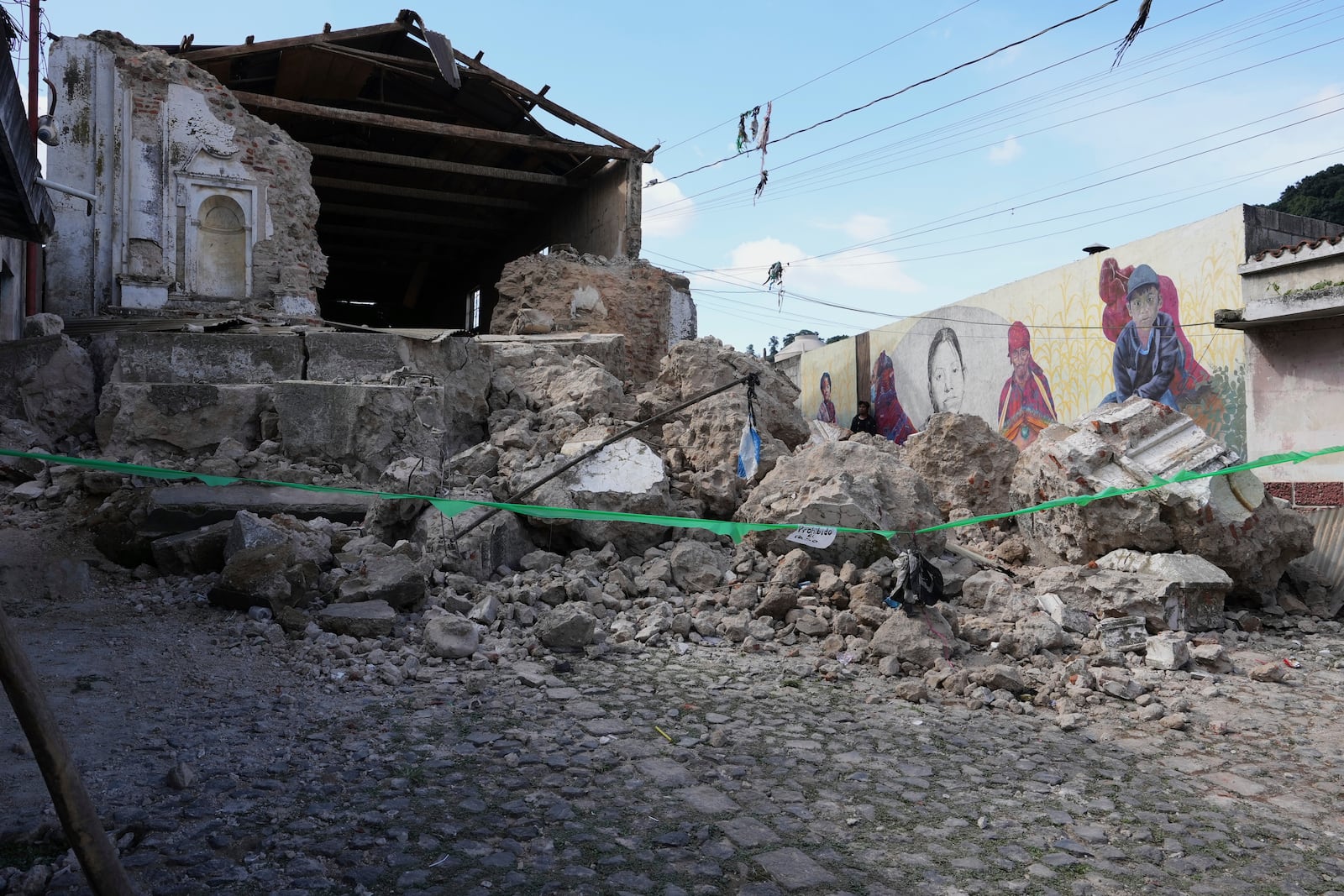 A man walks past the damaged Catholic Church El Calvario in Santa Maria de Jesus, Guatemala, Wednesday, July 9, 2025, following dozens of earthquakes and aftershocks that were recorded in a matter of hours. (AP Photo/Moises Castillo)