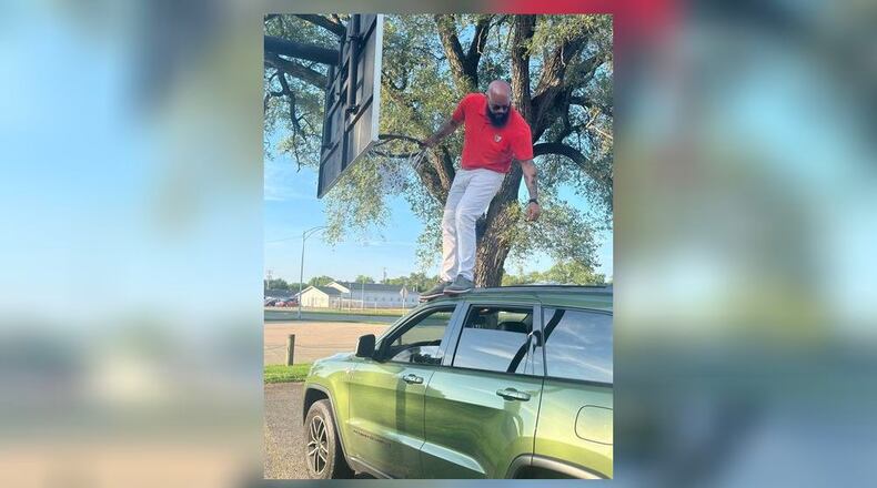 Cedric Burns-Davis, 38, stands on top of his Jeep as he installs a new basketball net at one of the city parks. He has replaced about 15 nets so far. CONTIBUTED