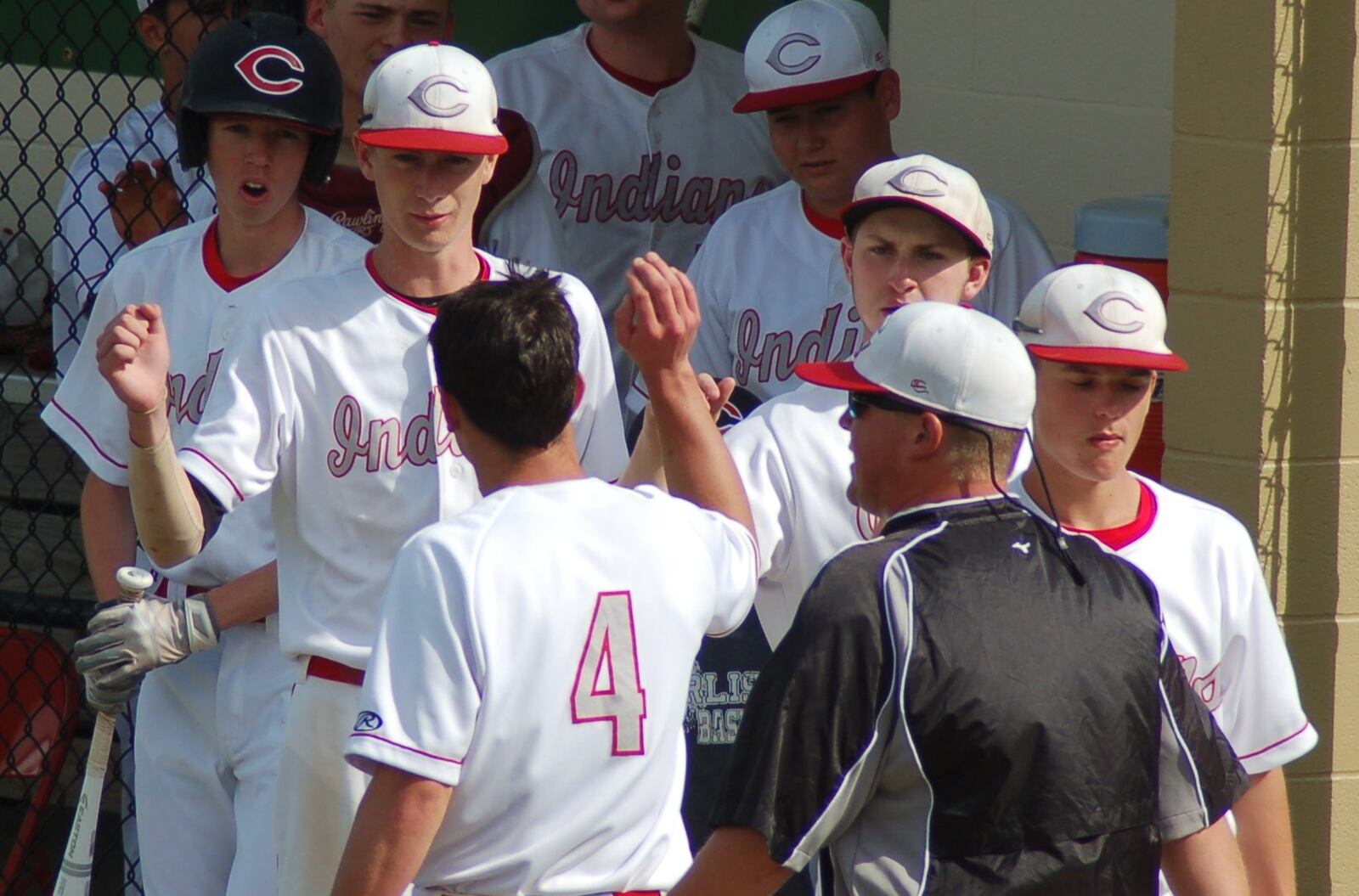 Adam Goodpaster (4) is greeted by his teammates after scoring Carlisle’s first run during its Division III sectional final against Brookville on Wednesday at Northmont. CONTRIBUTED PHOTO BY JOHN CUMMINGS
