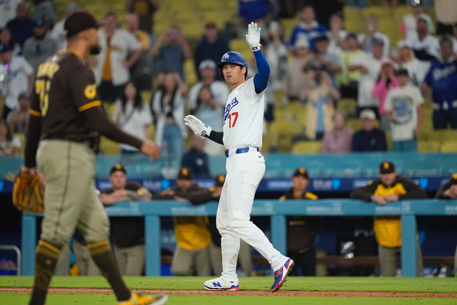 Los Angeles Dodgers' Shohei Ohtani, right, waves toward the dugout after being hit by a pitch thrown by San Diego Padres relief pitcher Robert Suarez, left, during the ninth inning of a baseball game Thursday, June 19, 2025, in Los Angeles. (AP Photo/Mark J. Terrill)