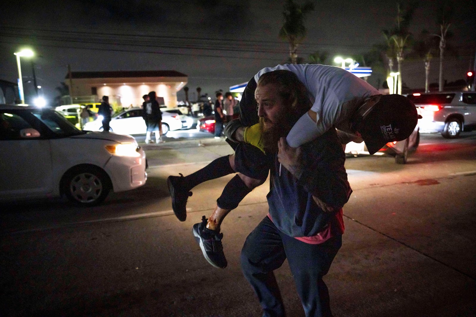A person carries an injured protester to cover during a protest in Compton, Calif., Saturday, June 7, 2025, after federal immigration authorities conducted operations. (AP Photo/Ethan Swope)