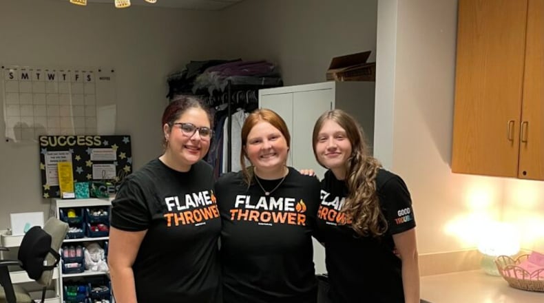 Butler Tech junior Madilyn Thompson (center) created a philanthropic program dubbed “Care Closet” that recently saw its one-year anniversary marked by a growing inventory of free, personal care items, clothing and shoes made available to fellow students at the D. Russel Lee campus can’t afford such necessities. She is pictured in the Care Closet room at her school with classmate volunteers Clara Jamison (left) and Amora Higgins. (Provided)