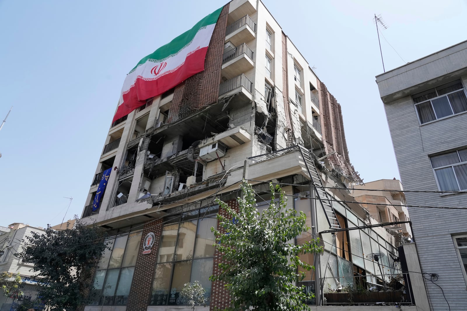 An Iranian flag hangs on a building which was hit by an Israeli strike last week, in Tehran, Iran, Wednesday, June 25, 2025. (AP Photo/Vahid Salemi)