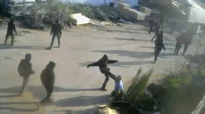 This frame grab from security camera footage filmed Jan. 8, 2025, and obtained by The Associated Press, shows men dressed mostly in black with their faces covered, one of whom is kicking a man on the ground as he tried to flee a nursery in the northern West Bank village of Deir Sharaf. Two people who witnessed the attack and are members of the family that owns the facility said the assailants were Israeli settlers beating 67-year-old Basim Saleh Yassin.(UGC via AP)