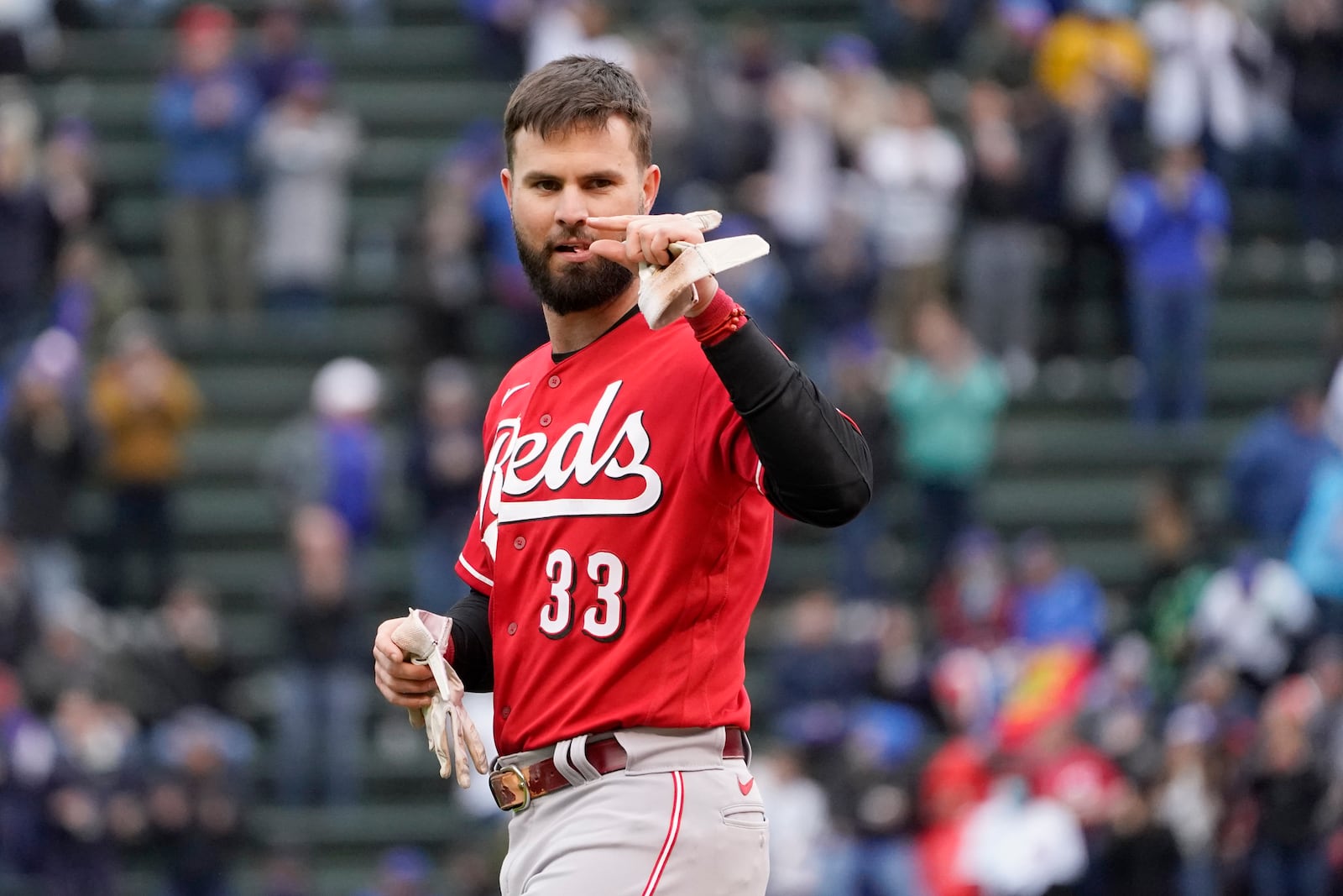 Cincinnati Reds' Jesse Winker gestures over to Chicago Cubs third base coach Willie Harris in the dugout during the fourth inning of a baseball game Friday, May 28, 2021, in Chicago. (AP Photo/Charles Rex Arbogast)