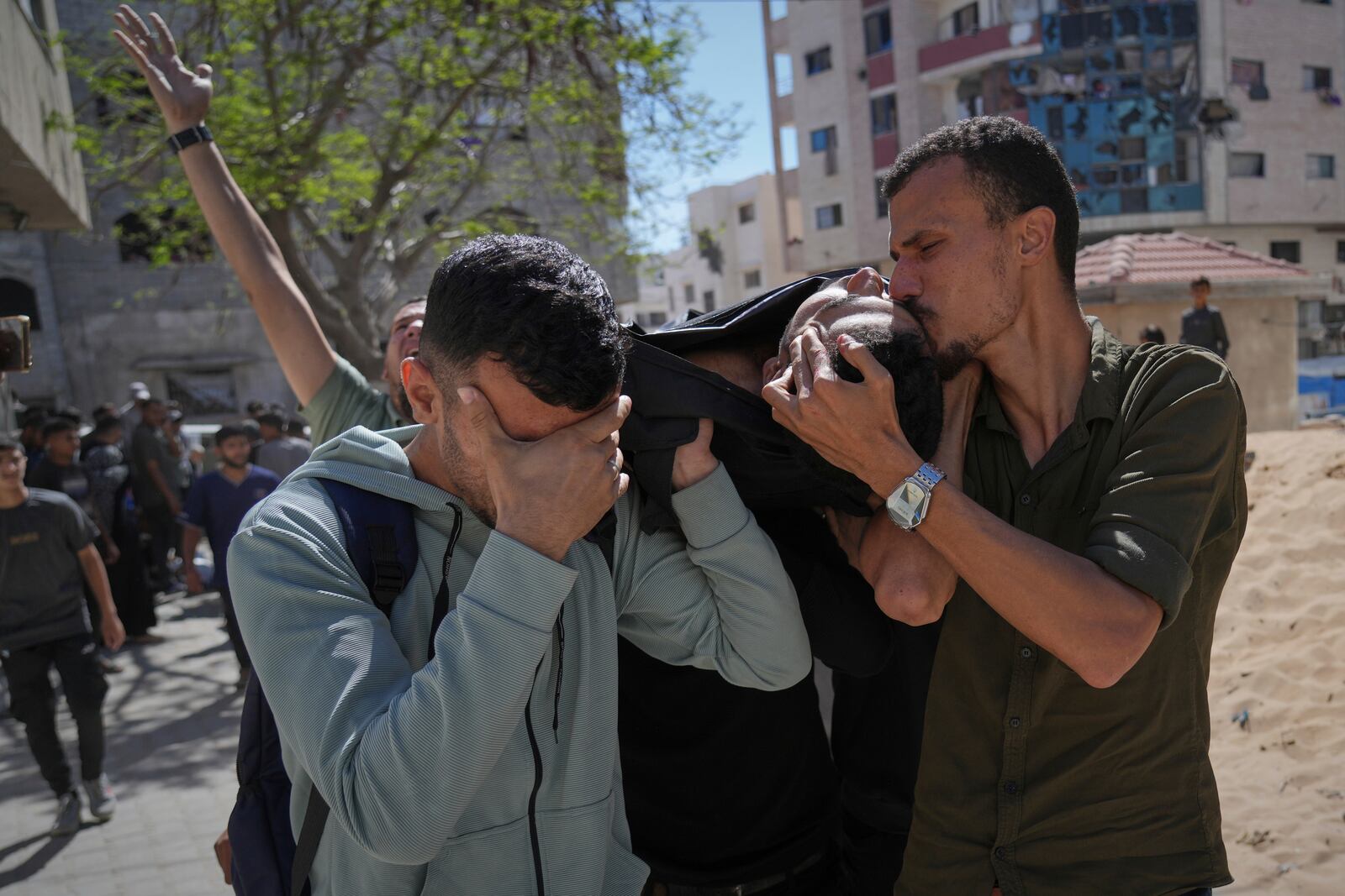 A man kisses the body of a victim of an Israeli army strike on a restaurant, which killed at least 29 people, as he is taken from the scene to the Shifa hospital in Gaza City, Wednesday, May 7, 2025.(AP Photo/Jehad Alshrafi)