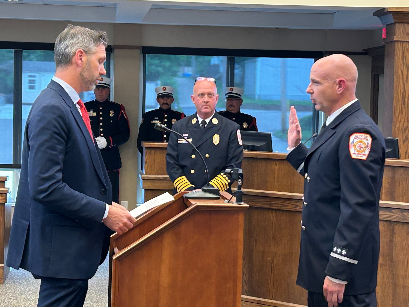 Monroe's Law Director Jack Hemenway, left, swears in Joe Locke as the city's new assistant fire chief during Tuesday's city council meeting. Fire Chief David Leverage looks on. RICK McCRABB/CONTRIBUTOR