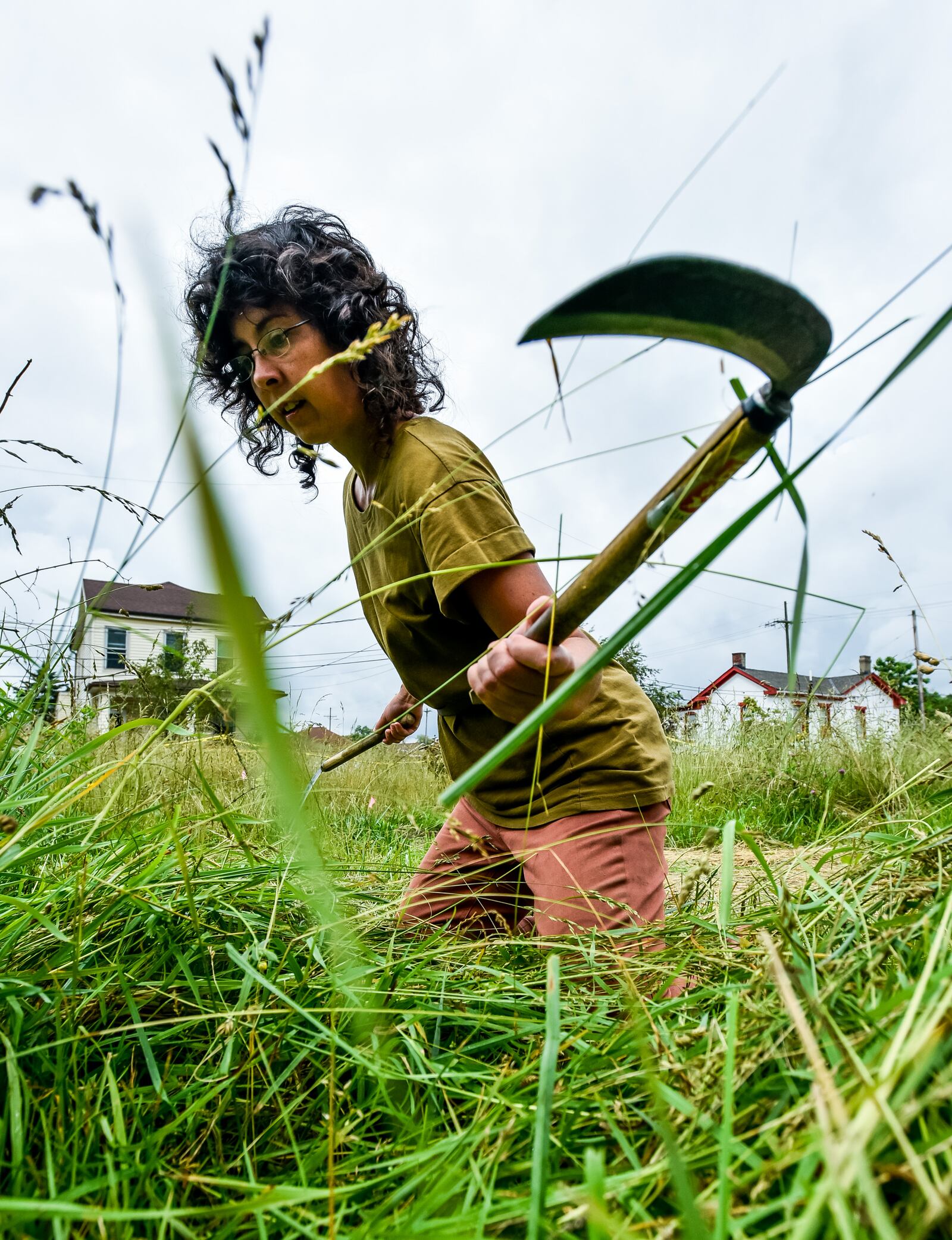 Laurana Wong uses hand scythes to cut tall grass Monday, June 7, 2021 on Wilson Street in Hamilton. Wong plans on turning the vacant lot into secluded garden spaces called Flora Nature Rooms. NICK GRAHAM / STAFF