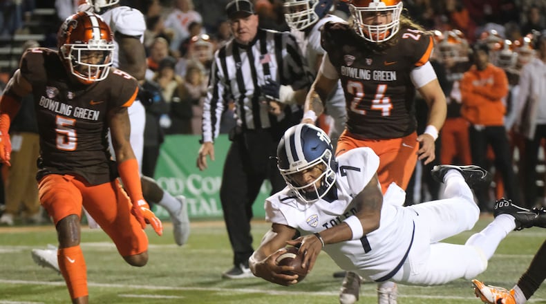 Toledo quarterback Dequan Finn dives into the end zone for a touchdown past Bowling Green's Sy Dabney (5) and Diego Neri during the first half of an NCAA college football game Wednesday, Nov. 10, 2021, in Bowling Green, Ohio. (J.D. Pooley/Sentinel-Tribune via AP)