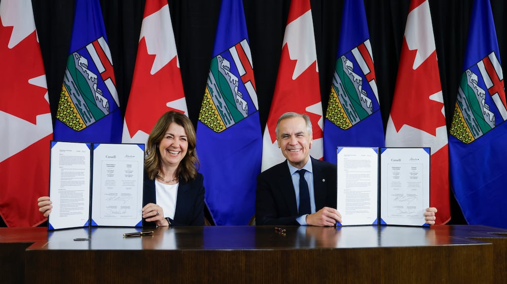 Prime Minister Mark Carney, right, signs an MOU with Alberta Premier Danielle Smith in Calgary, Alta., Thursday, Nov. 27, 2025. (Jeff McIntosh /The Canadian Press via AP)