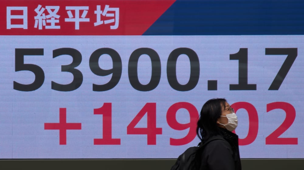 A person walks near a stock price monitor showing Nikkei index at a security company Tuesday, March 17, 2026, in Tokyo. (AP Photo/Eugene Hoshiko)