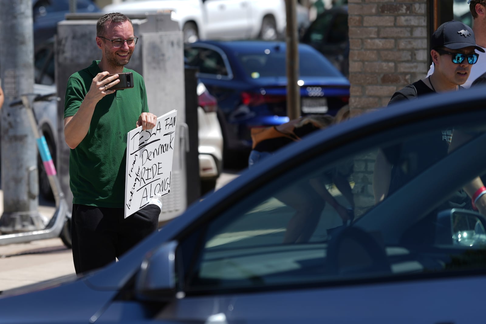 Torkild Johansen of Denmark takes photos of a driverless Tesla robotaxi, a ride-booking service, Sunday, June 22, 2025, in Austin, Texas. (AP Photo/Eric Gay)