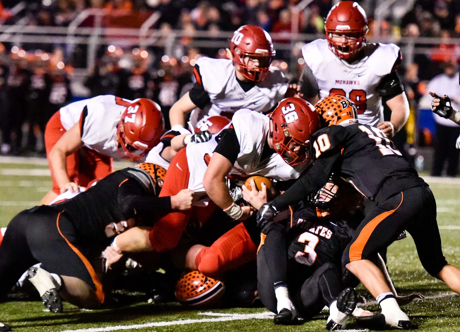 Wheelersburg’s Bryson Keeney (10) and Trey Carter (3) are among the defenders trying to bring down Madison’s Cole Pelgen on a run during Friday night’s Division V state semifinal at Herrnstein Field in Chillicothe. NICK GRAHAM/STAFF