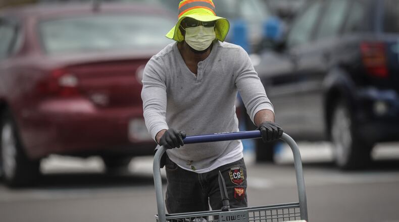 Chris Carlisle of Dayton pushes his cart after shopping at Lowes in Trotwood. Carlisle said he’s concerned about being profiled when he wears his protective mask in public. JIM NOELKER/STAFF