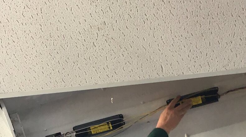 Jim Pate installs new lighting at the Serve City homeless shelter in Hamilton. MIKE RUTLEDGE/STAFF