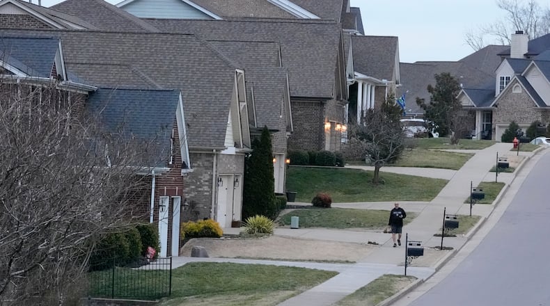 A person walks past single family homes, Tuesday, Feb. 10, 2026, in Nashville, Tenn. (AP Photo/George Walker IV)