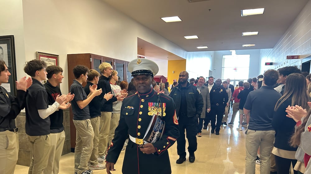 Ret. Staff Sgt. Jerry Ferris, who served two tours in Vietnam in the U.S. Marines, walks down the hallway Tuesday morning as Fenwick High School students applaud him and other veterans as they leave the school's annual Veterans Day breakfast. RICK McCRABB/CONTRIBUTOR
