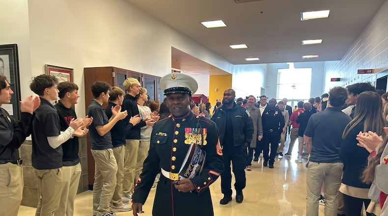 Ret. Staff Sgt. Jerry Ferris, who served two tours in Vietnam in the U.S. Marines, walks down the hallway Tuesday morning as Fenwick High School students applaud him and other veterans as they leave the school's annual Veterans Day breakfast. RICK McCRABB/CONTRIBUTOR