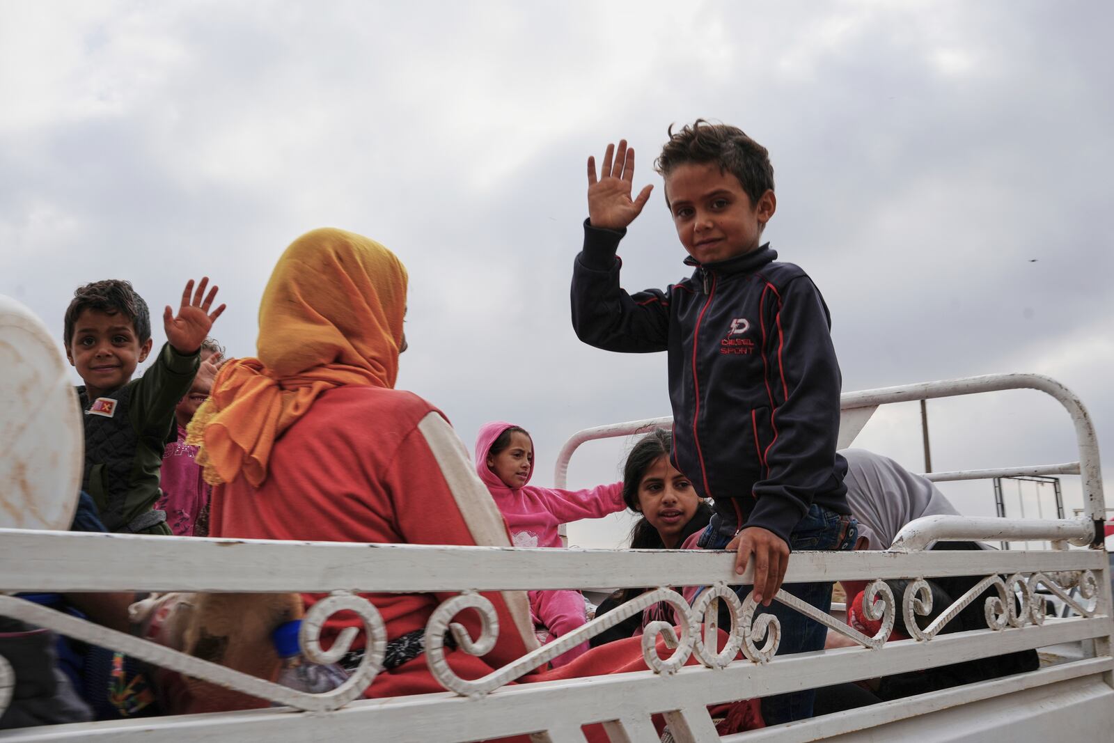Syrian Bedouin families gesture as they ride in a convoy led by Red Crescent vehicles in Busra al-Harir, heading to Daraa after being evacuated from Sweida following more than a week of violent clashes, Monday, July 21, 2025. (AP Photo/Malek Khattab)