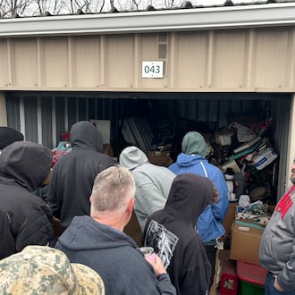 Auctioneer Justin Steel, far right, lets potential bidders look inside a storage unit at Rock Castle Storage, 2901 S. Breiel Blvd., Middletown. Those who store their items were months behind on their rent, according to a manager at the storage unit. RICK McCRABB/CONTRIBUTOR