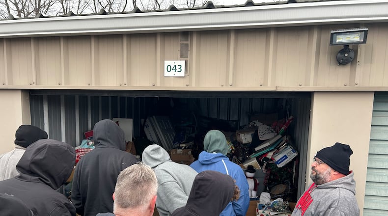 Auctioneer Justin Steel, far right, lets potential bidders look inside a storage unit at Rock Castle Storage, 2901 S. Breiel Blvd., Middletown. Those who store their items were months behind on their rent, according to a manager at the storage unit. RICK McCRABB/CONTRIBUTOR