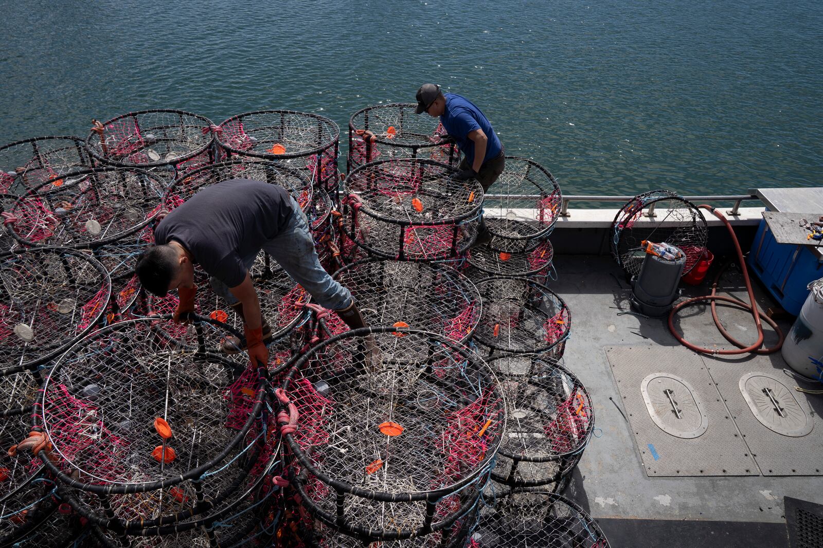 Hunter Nguyen, right, and Jonathan Tin, load crab traps onto the boat Pale Horse at Pier 45 in San Francisco, Thursday, April 10, 2025. The boat's crew is trying out pop-up gear aimed at preventing whale entanglements. (AP Photo/Emily Steinberger)