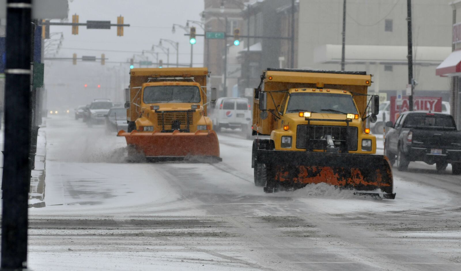Two snow plows on Monday morning drive down Main Street approaching B Street in Hamilton. (MICHAEL D. PITMAN / STAFF)