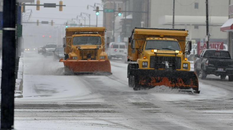 Two snow plows on Monday morning drive down Main Street approaching B Street in Hamilton. (MICHAEL D. PITMAN / STAFF)