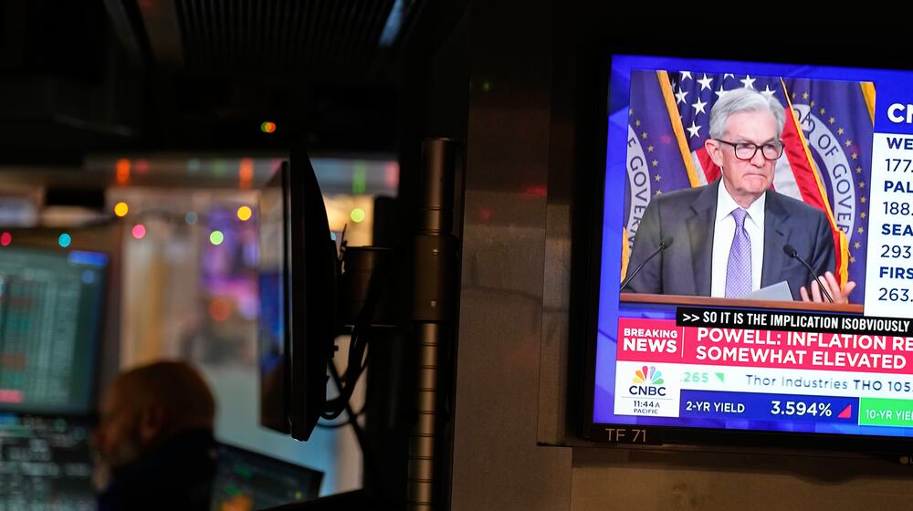 A television on the floor at the New York Stock Exchange in New York, display a news conference with Fed chairman Jerome Powell, Wednesday, Dec. 10, 2025. (AP Photo/Seth Wenig)