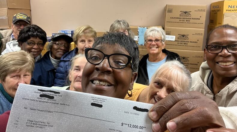 Pam Benson holds a donation check for $12,000. Benson, the director of New Miami's Village Food Pantry, received the check after a Journal-News article on her organization's efforts. CONTRIIBUTED