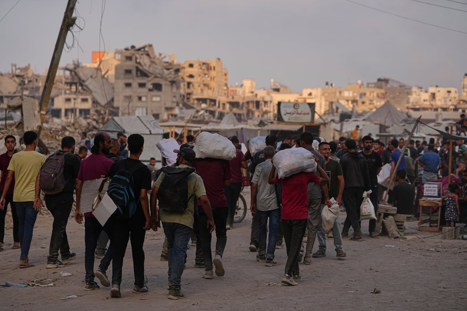 Palestinians carry sacks of food and humanitarian aid unloaded from trucks convoy that had been heading to Gaza City, in the northern Gaza Strip, Sunday, June 22, 2025. (AP Photo/Jehad Alshrafi)