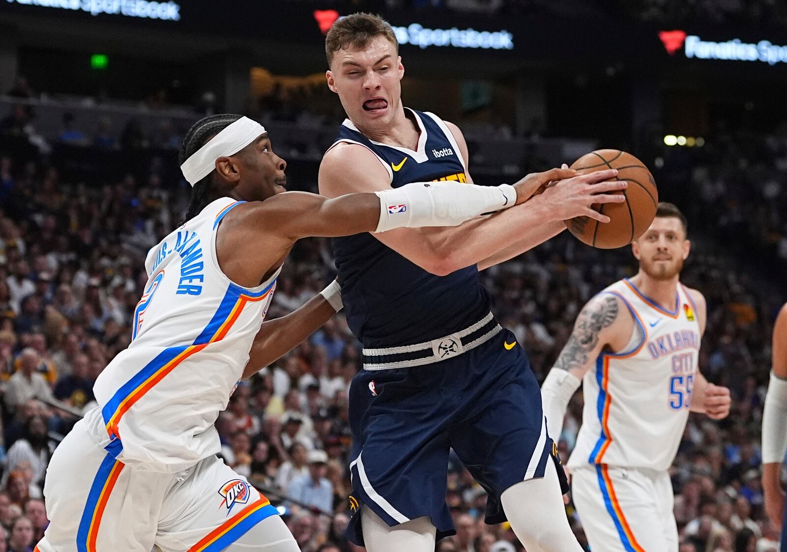 Oklahoma City Thunder guard Shai Gilgeous-Alexander, left, blocks Denver Nuggets guard Christian Braun, front right, on the way to the basket in the first half of Game 4 in the Western Conference semifinals of the NBA basketball playoffs Sunday, May 11, 2025, in Denver. (AP Photo/David Zalubowski)