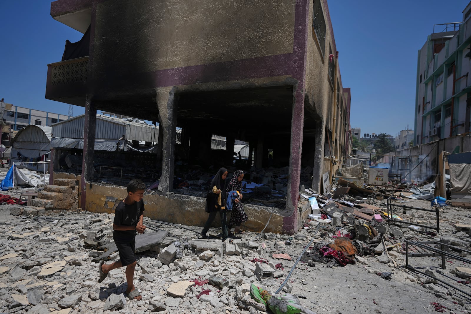 Palestinians survey the destruction at a school used as a shelter after it was struck by an Israeli airstrike in Gaza City, on Thursday, July 3, 2025. (AP Photo/Jehad Alshrafi)