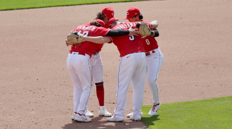 Reds infielders celebrate after a victory against the Pirates on Wednesday, April 7, 2021, at Great American Ball Park in Cincinnati. David Jablonski/Staff