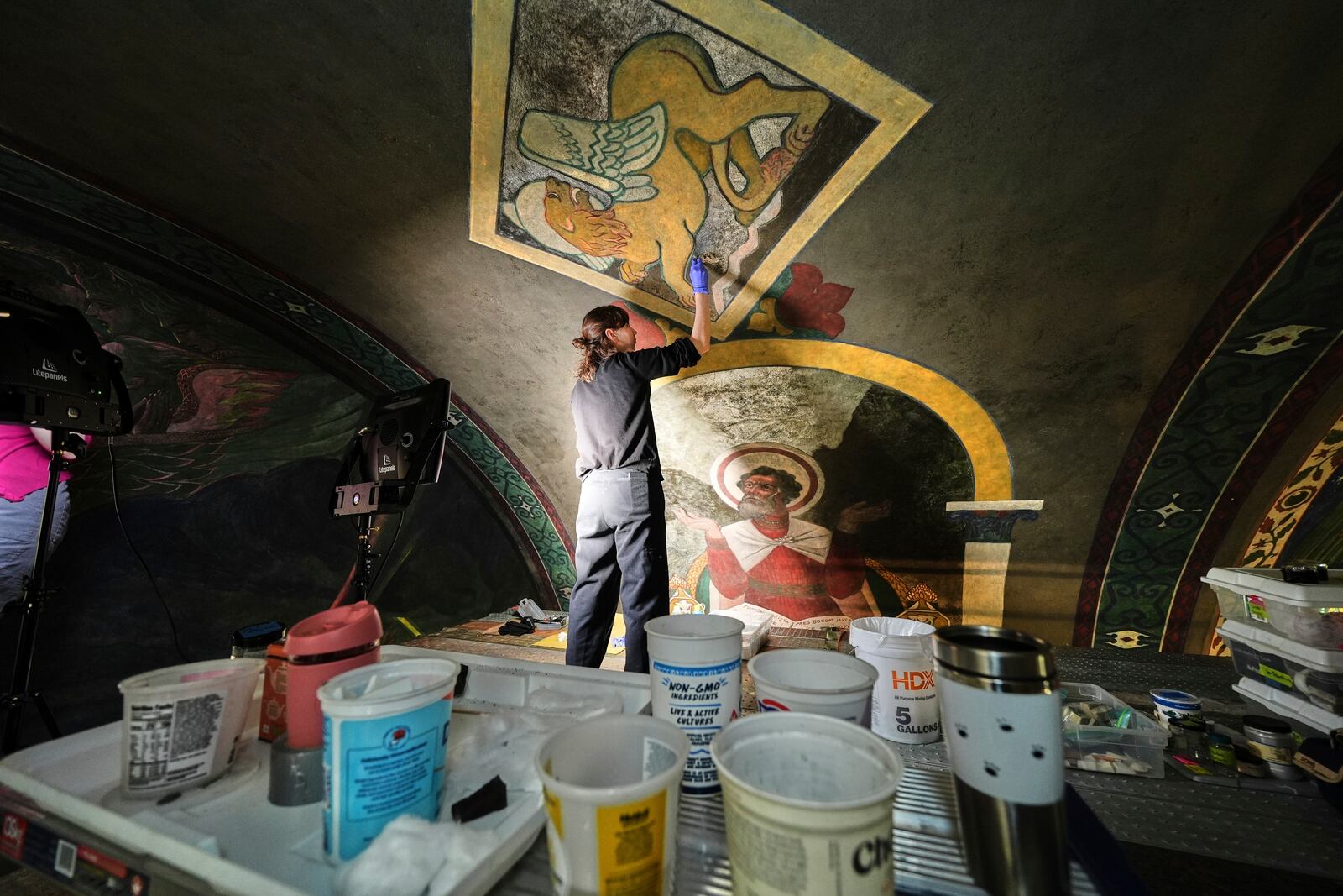Standing on a 32-foot-tall scaffold, art conservationist Kate Pirelli works on cleaning a mural by Max Vanka depicting a lion and St. Mark inside St. Nicholas Croatian Catholic Church in Millvale, Pa., Monday, May 19, 2025. (AP Photo/Gene J. Puskar)