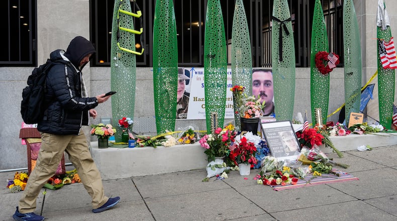 A person walks past a makeshift memorial for U.S. Army Spc. Sarah Beckstrom and U.S. Air Force Staff Sgt. Andrew Wolfe outside of Farragut West Station, near the site where the two National Guard members were shot, Monday, Dec. 1, 2025, in Washington. (AP Photo/Julia Demaree Nikhinson)