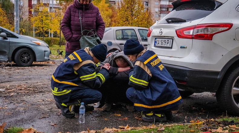 Emergency workers comfort a man who lost his son in Russia's drone attack that hit residential buildings in Kyiv, Ukraine, Sunday, Oct. 26, 2025. (AP Photo/Dan Bashakov)