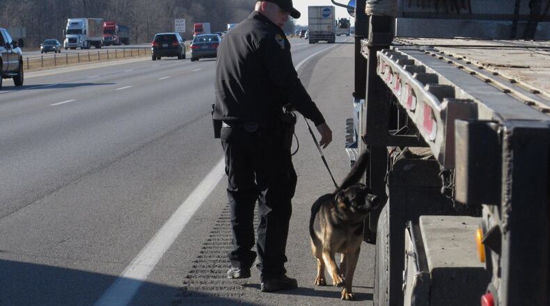Trooper Mike Wilson of the Ohio State Highway Patrol leads his drug-sniffing dog partner Pluto, a Dutch shepherd, past a truck stopped on I-70 in Madison County in 2016. Associated Press 2016
