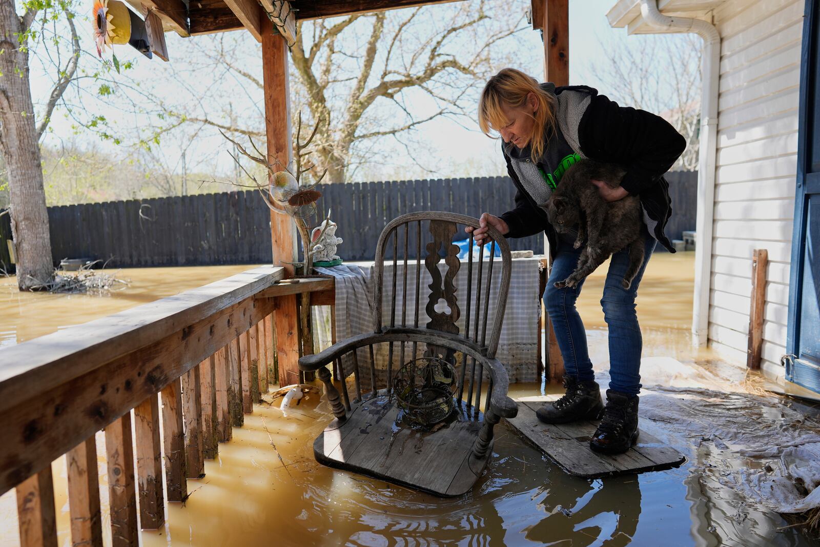 Wanona Harp rescues a cat stranded on her neighbor's porch flooded by the Kentucky River in Lockport, Ky., Tuesday, April 8, 2025. (AP Photo/Carolyn Kaster)