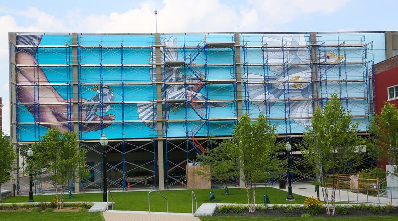 Miami University Hamilton art instructor Nicole Trimble and her team of volunteers is transforming a parking garage wall overlooking Rotary Park in downtown Hamilton into a brilliantly colorful mural. GREG LYNCH / STAFF