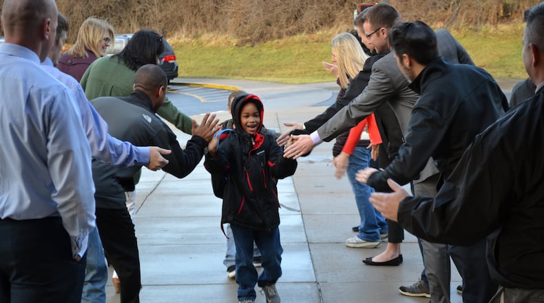 Brendyn Carter - a kindergarten student at Lakota’s Shawnee Early Childhood Center - is greeted arriving to school as part of the school system’s new fanfare events. Adult residents, school staffers and local business people are invited to form a greeting tunnel to encourage students and show them the importance of education. CONTRIBUTED