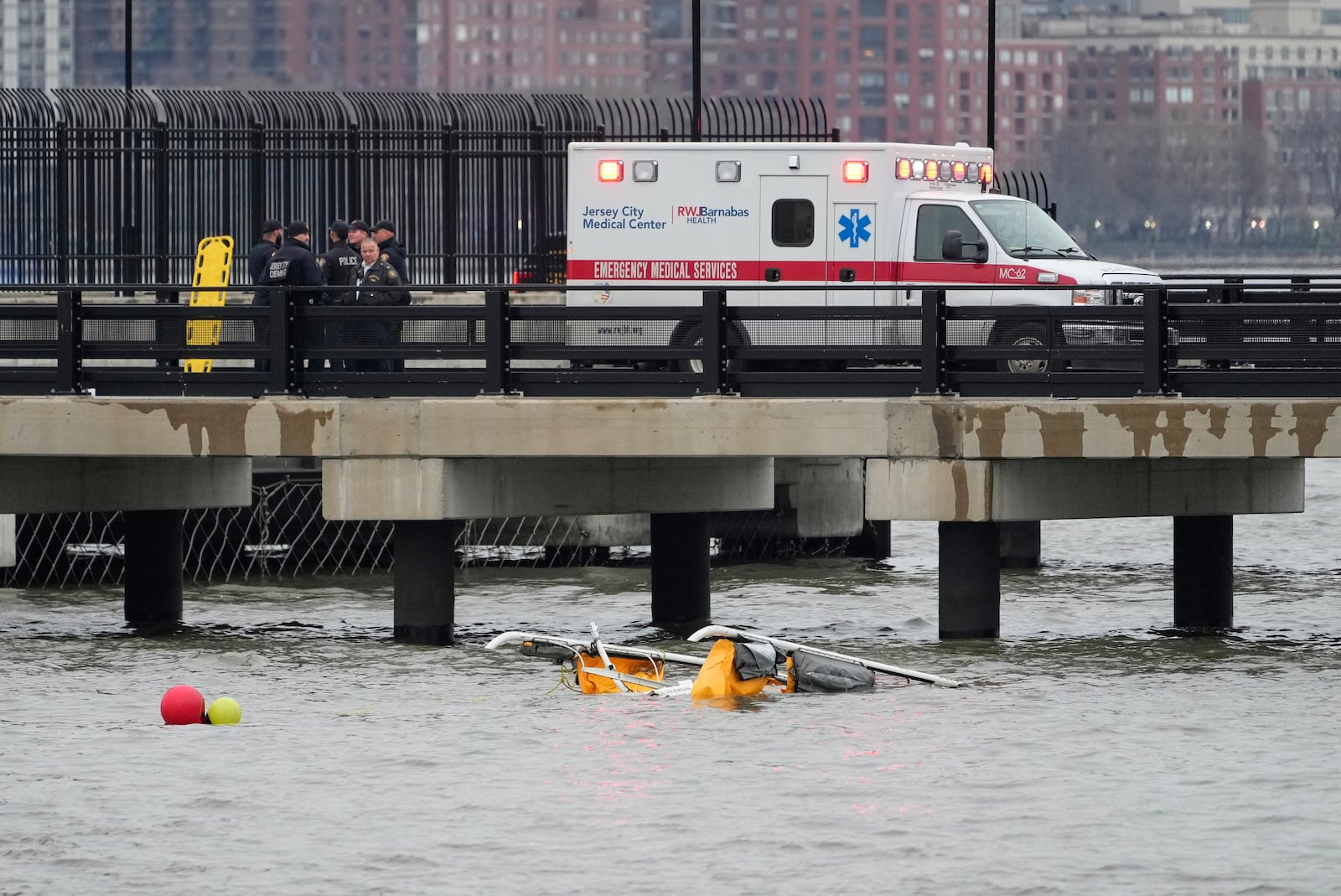 First responders stand on a pier at the scene where a helicopter crashed into the Hudson River, Thursday, April 10, 2025, in Jersey City, N.J. (AP Photo/Seth Wenig)
