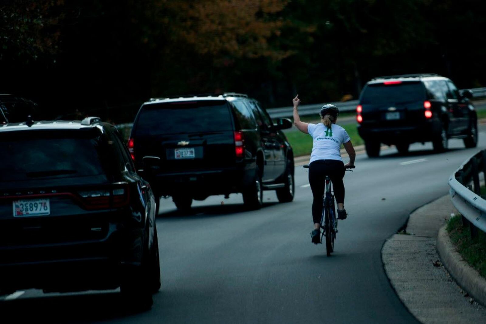 Juli Briskman gestures with her middle finger as a motorcade with President Donald Trump departs Trump National Golf Course in Sterling, Va., Oct. 28, 2017.