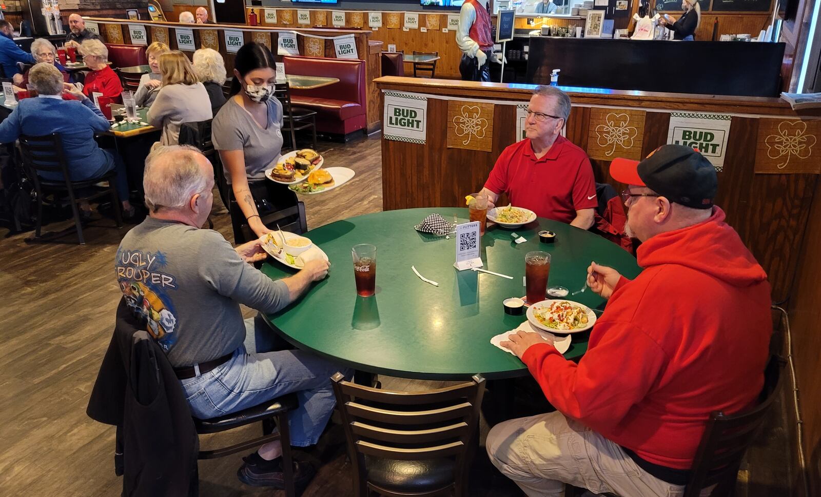 Waitress Mya Hogeback serves food to Bruce Taylor, left, Brian Taylor and Rod McGaha, right, Thursday at Putters Sports Grill in Liberty Twp. Owner Jan Collins closes the restaurant every Monday to save on overhead. NICK GRAHAM/STAFF