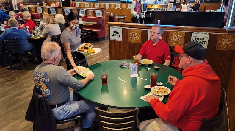 Waitress Mya Hogeback serves food to Bruce Taylor, left, Brian Taylor and Rod McGaha, right, Thursday at Putters Sports Grill in Liberty Twp. Owner Jan Collins closes the restaurant every Monday to save on overhead. NICK GRAHAM/STAFF