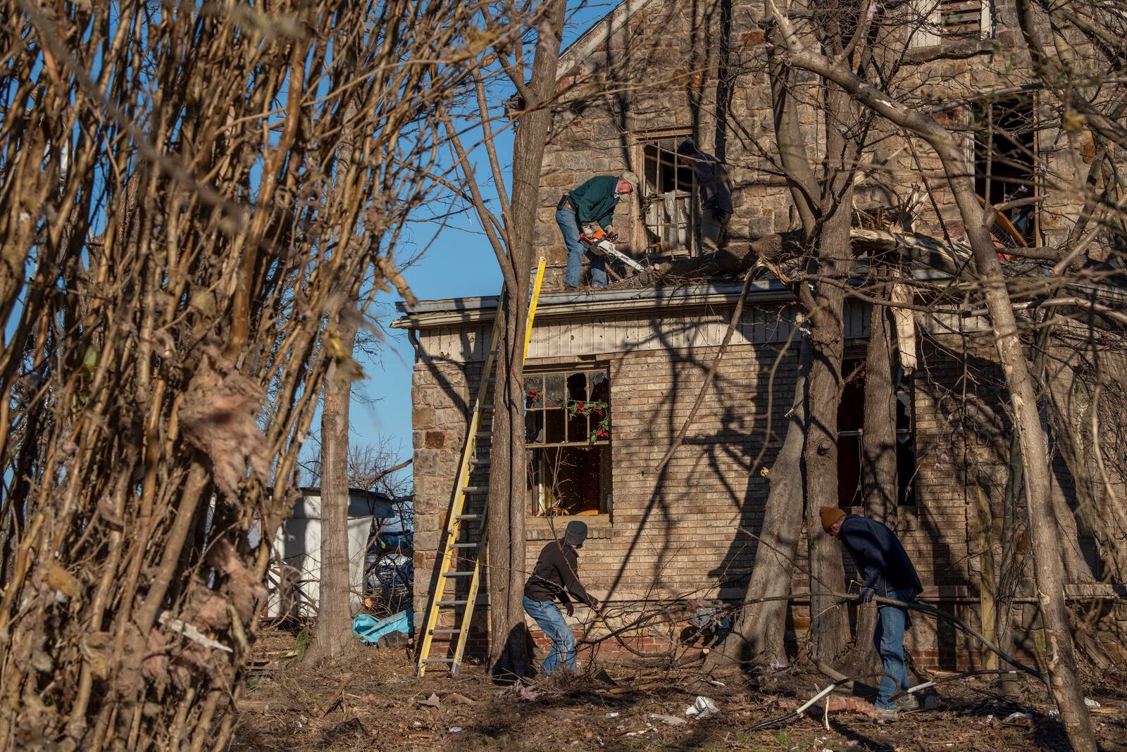 Trees and debris are removed from a home in Mayfield, Ky. on Monday, Dec. 13, 2021, after a tornado swept across the region. Determining how many people died in the tornadoes that ravaged the central U.S. on Friday has been a challenging task so far, with estimates fluctuating as search teams continue to spread out amid vast fields of rubble in an effort to rescue the living and account for the dead. (Johnny Milano/The New York Times)